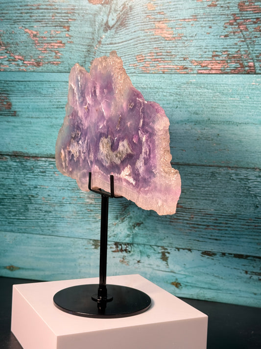 Pink, purple, and blue Fluorite crystal slab on a modern black stand, used as elegant home decor