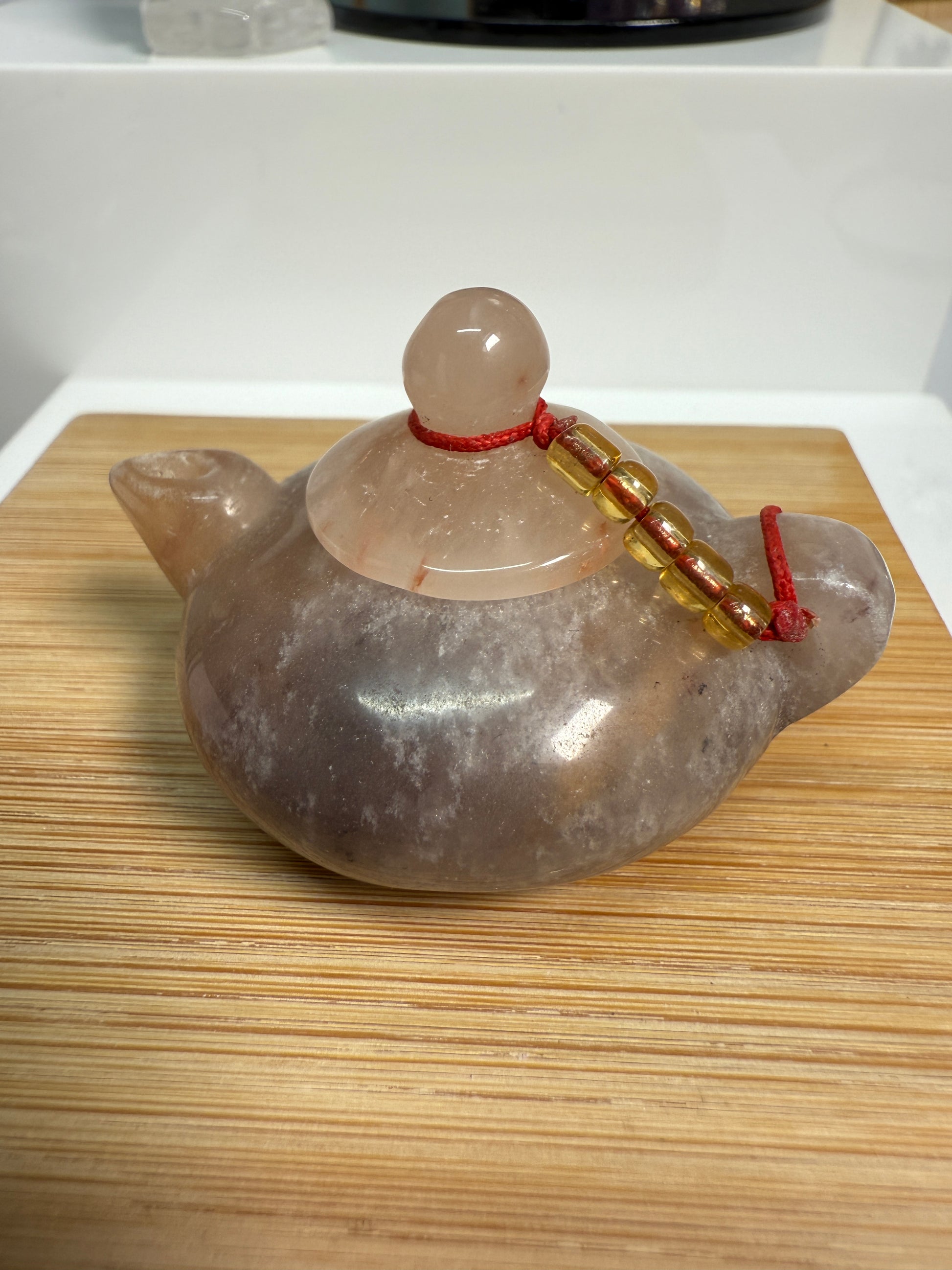Purple Jade teapot-shaped crystal carving, 2-inch miniature with rich lavender tones, styled on a flat wood surface as a charming display piece.